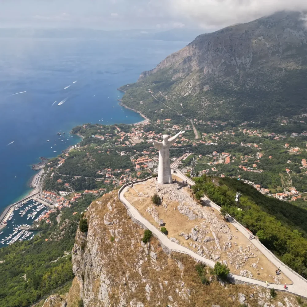 Vista aerea di un monumento su una collina con vista su una città costiera e un porto.